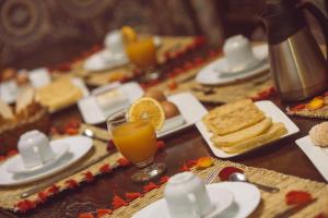 a table topped with plates of food and a glass of orange juice at Riad Sable Chaud in Marrakesh