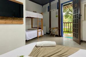 a bedroom with a bed and a bunk bed with a tv at Vila Pequeá Ilhabela in Ilhabela