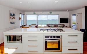 a kitchen with a stove and a living room at Shoreside - Tutukaka Holiday Home in Tutukaka