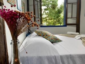a vase of flowers sitting on top of a bed at Vila Pequeá Ilhabela in Ilhabela