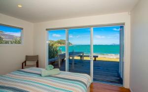 a bedroom with a bed and a view of the ocean at Shoreside - Tutukaka Holiday Home in Tutukaka