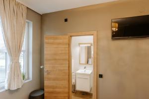 uma casa de banho com um lavatório e uma porta com um espelho em Rooms VERDE em Petrovče