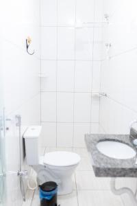 biała łazienka z toaletą i umywalką w obiekcie Pousada DDB w mieście Resende Costa