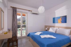 a bedroom with a blue bed with two towels on it at Castello Apartments in Stalida