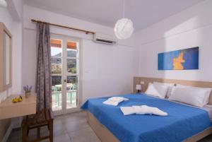 ein Schlafzimmer mit einem blauen Bett mit zwei Handtüchern darauf in der Unterkunft Castello Apartments in Stalida