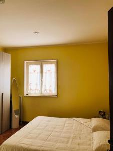 a yellow bedroom with a bed and a window at La villetta senza tempo in Aprilia