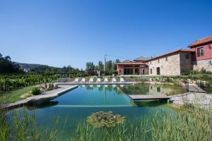 un jardin avec un étang en face d'un bâtiment dans l'établissement Quinta do Minhoto, à Fafe