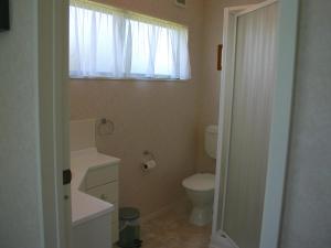 Un baño con inodoro y ventana. en Waihi Getaway - Waihi Beach Holiday Home, en Waihi Beach 9 fotos más