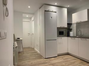 a kitchen with white cabinets and a refrigerator at VUT La Plaza in El Barraco