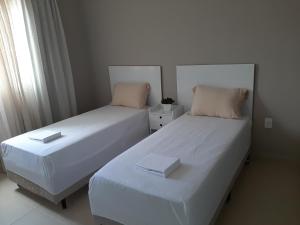 2 nebeneinander sitzende Betten in einem Schlafzimmer in der Unterkunft Apartamento em Tijucas próximo a praias in Tijucas