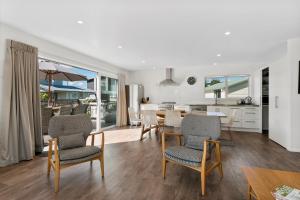 eine Küche und ein Wohnzimmer mit einem Tisch und Stühlen in der Unterkunft The Waihi Beach House - Waihi Beach Holiday Home in Waihi Beach