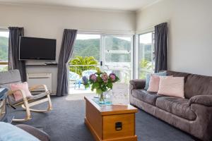 a living room with a couch and a vase of flowers at Tirohanga Wai - Waikawa Holiday Home in Waikawa