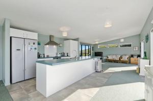 een keuken met witte apparatuur en een woonkamer bij The Blue Cottage with WiFi- Waipu Holiday Home in Waipu