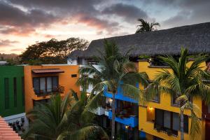 a group of buildings with palm trees in front of them at El Pueblito Sayulita - Colorful, Family and Relax Experience with Private Parking and Pool in Sayulita
