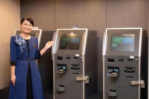 a woman standing in front of two atm machines at Richmond Hotel Sapporo Ekimae in Sapporo