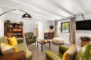 a living room with green chairs and a tv at Wanaka Stone Cottage - Wanaka Holiday Home in Wanaka