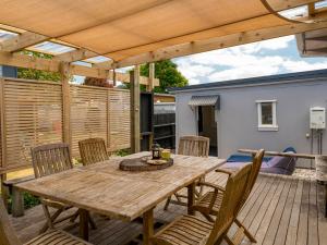 una mesa de madera y sillas en una terraza de madera en Pipi Palace - Whangamata Bach, en Whangamata