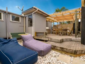 patio con sofá y terraza de madera en Pipi Palace - Whangamata Bach, en Whangamata