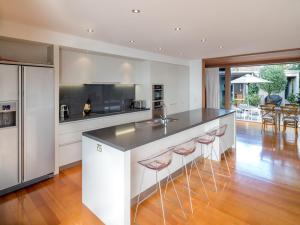 a kitchen with white cabinets and a counter with bar stools at The Breakers - Whangapoua Executive Holiday Home in Whangapoua