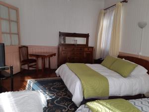 a bedroom with two beds and a table and a television at Hospedaje Mery in Cañete