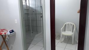 a glass shower door with a white chair in a room at Edifício Belio in Cascavel
