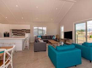 uma sala de estar com sofás azuis e uma cozinha em Tattletails Rest - Whitianga Holiday House em Whitianga