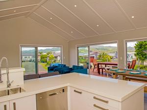 an open kitchen and living room with views of a patio at Tattletails Rest - Whitianga Holiday House in Whitianga