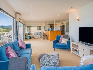 a living room with a blue couch and a tv at Seaview Serenity- Whitianga Holiday Home in Whitianga