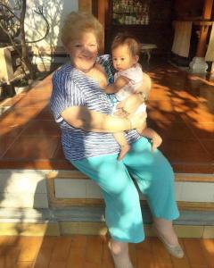 a woman sitting on a bench holding a baby at Gina's guest house in Sanur