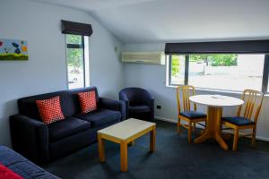 a living room with a couch and a table and chairs at ASURE Central Gold Motel Cromwell in Cromwell