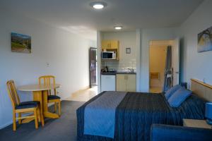 ASURE Central Gold Motel Cromwell في كرومويل: غرفة نوم بسرير وطاولة ومطبخ