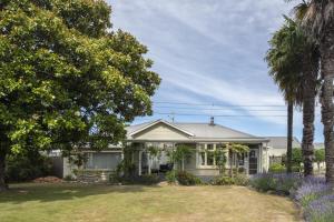 a white house with palm trees in front of it at U Studios Masterton in Masterton