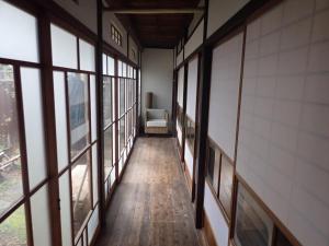a hallway with windows and a chair in a building at Kominka Guesthouse Hagi Akatsukiya in Hagi