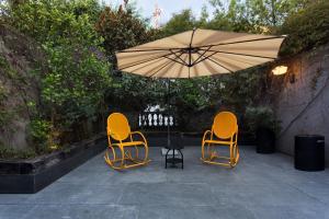 Casa 9 في مدينة ميكسيكو: كرسيين وطاولة مع مظلة على الفناء