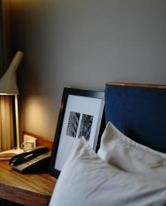 a desk with a bed with a picture and a phone at Kollektiv Hotel in Bandung