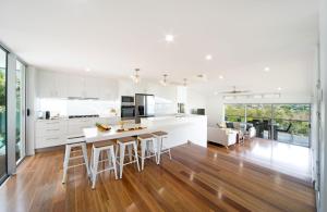 a kitchen with white cabinets and a kitchen island with bar stools at Oleander Holiday Home - Airlie Beach in Airlie Beach
