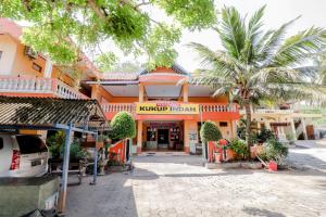 un edificio de naranjos con palmeras delante de él en Hotel Kukup Indah, en Kemadang