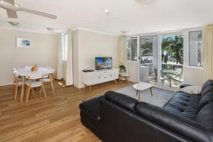 a living room with a black couch and a table at The Bay Apartments Coolangatta in Gold Coast