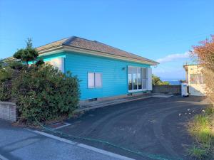 a blue house with a driveway in front of it at GANADAN Cottage in Kagoshima