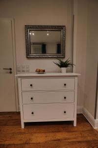 - une commode blanche avec un miroir sur un mur dans l'établissement Appartement Deluxe, à Worms