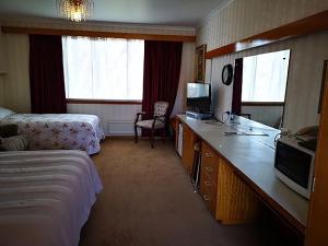 Pokój hotelowy z łóżkiem i biurkiem z telewizorem w obiekcie Motel Mayfair on Cavell w mieście Hobart