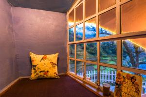 a room with a pillow and a large window at Zostel Plus Mussoorie- Kempty in Mussoorie