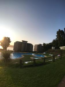 a park with a pond and buildings in the background at Departamentos Costa Pingueral in Tomé