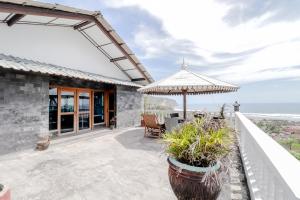 an outdoor patio with an umbrella and chairs at Adinda Beach Hotel and Villa in Bantul