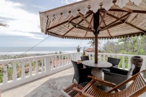uma mesa e cadeiras numa varanda com um guarda-sol em Adinda Beach Hotel and Villa em Bantul