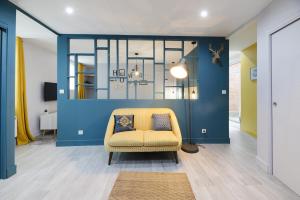 een woonkamer met een gele stoel en een blauwe muur bij Gîte de la Frête in Carvin