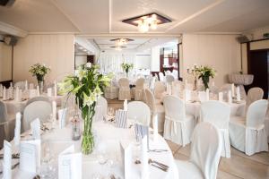 a room filled with white tables and chairs with flowers at Haus Fliederbusch in Borken