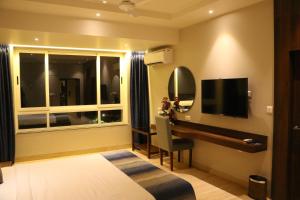 - une chambre avec un lit, un bureau et une télévision dans l'établissement Cosmique Clarks Inn Suites Goa, à Madgaon