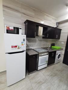 een keuken met zwarte kasten en een witte koelkast bij Margarita Hotel in Amman