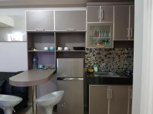 a kitchen with brown cabinets and a table with stools at Brand new and sweet @ apartemen parahyangan residence bandung in Bandung